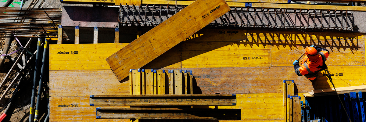 Håndværker står på stort byggeri med et reb spændt fast for at undgå arbejdsulykker og højne sikkerheden